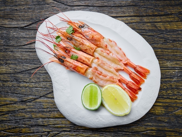 Аппетитные креветки на белой тарелке с лимоном
