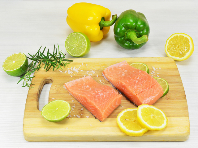 Красная рыба на разделочной доске с лимоном и перцем 