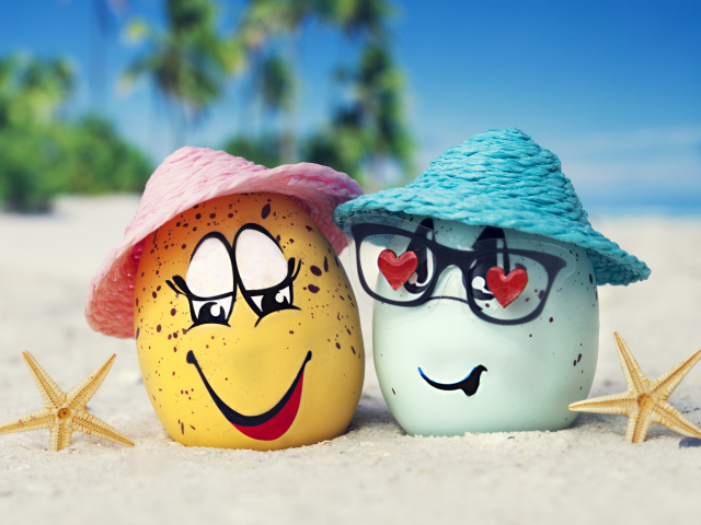 Два яйца в шляпах на песке с морскими звездами летом