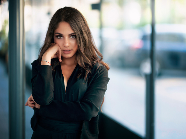 Милая девушка в черном наряде стоит на остановке