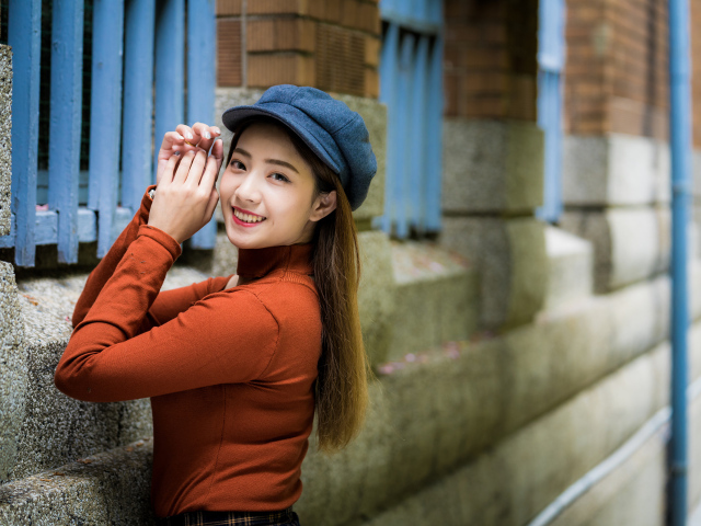 Девушка азиатка в кепке на стенке 