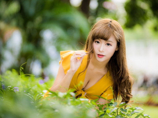 Девушка азиатка в желтом платье в парке 