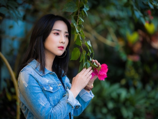 Девушка азиатка в джинсовой куртке в парке