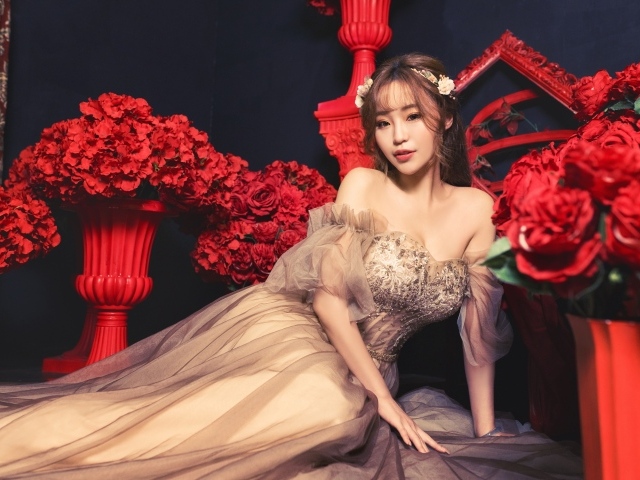 Азиатка в красивом платье в комнате с красными цветами