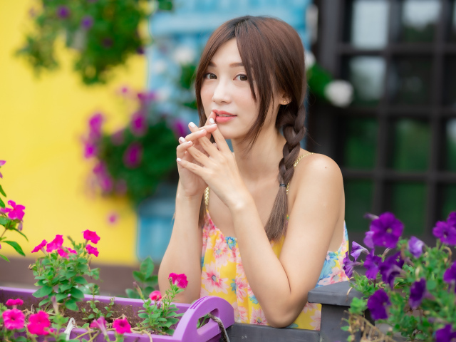 Красивая девушка Азиатка у цветов петунии