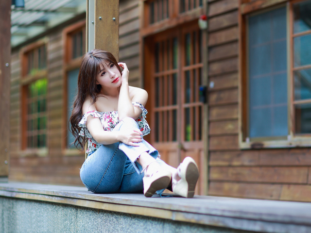 Красивая девушка азиатка сидит у дома