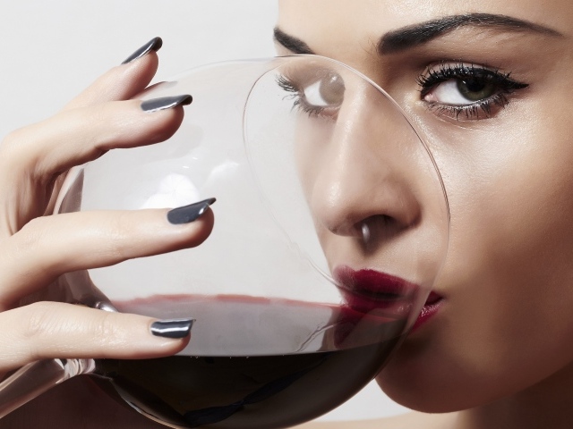 Красивая девушка пьет вино из бокала 