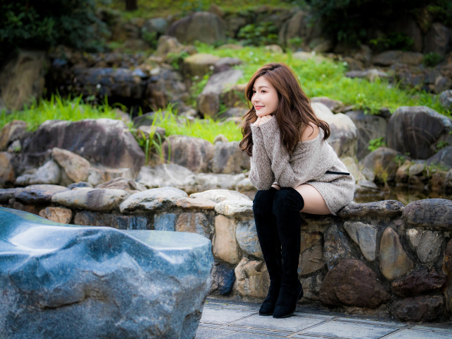 Красивая девушка в кофте сидит у пруда