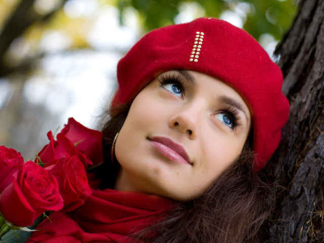 Красивая девушка в красном берете с букетом роз у дерева