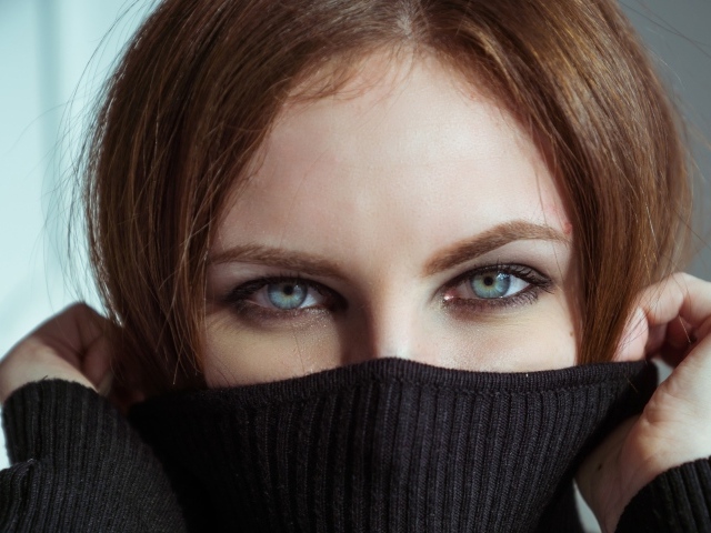 Красивая девушка с голубыми глазами закрыла лицо свитером 