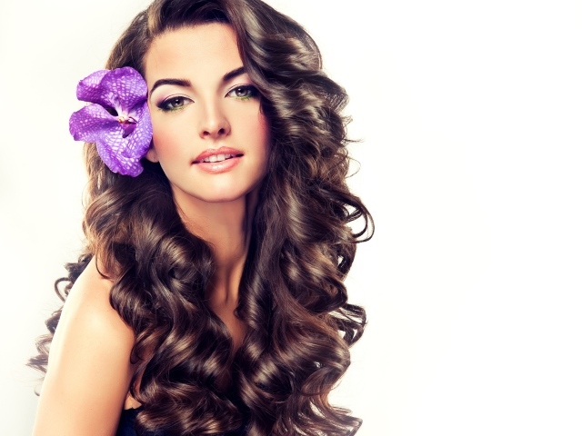 Красивая длинноволосая девушка с цветком в волосах на белом фоне