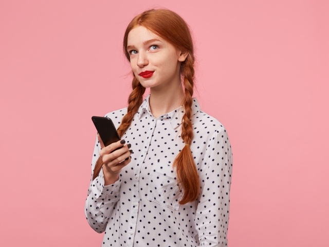 Красивая рыжеволосая девушка с косами на розовом фоне