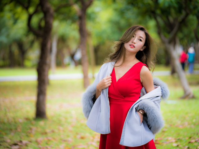Яркая девушка азиатка в красном платье в парке