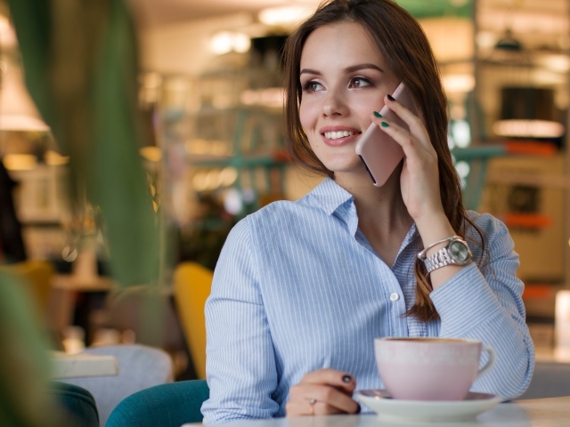 Деловая девушка в рубашке разговаривает в кафе по телефону