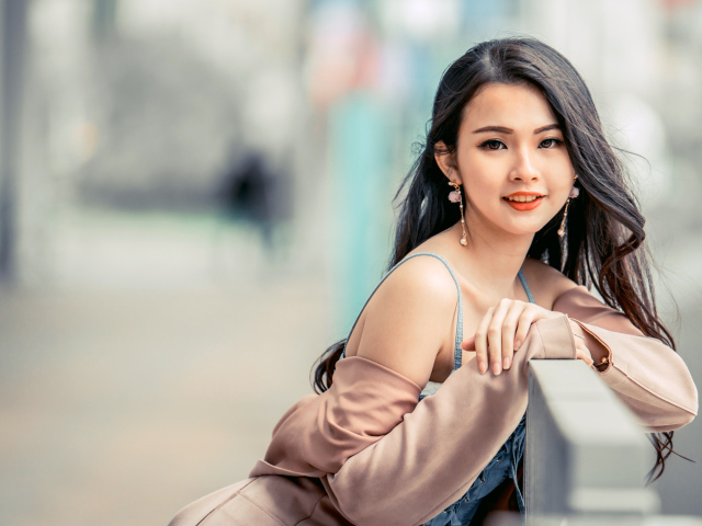 Очаровательная девушка азиатка сидит на лавке