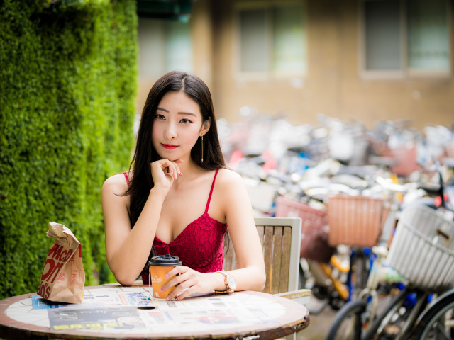 Милая девушка азиатка сидит за столиком в кафе
