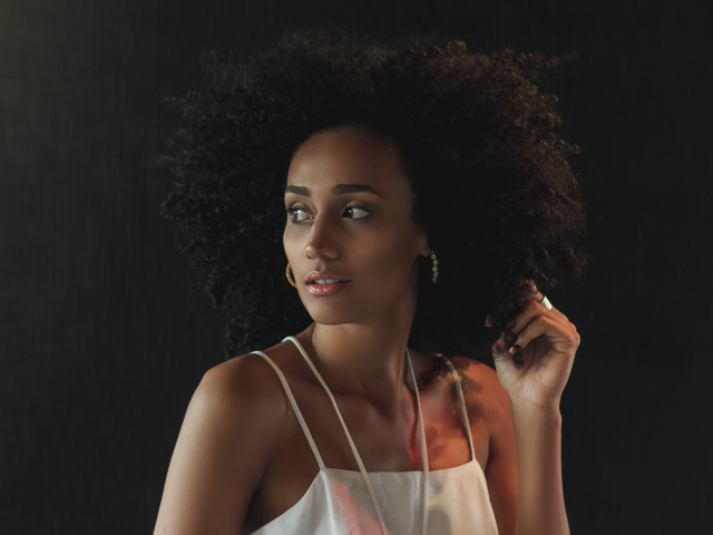 Темнокожая девушка с красивыми волосами на сером фоне