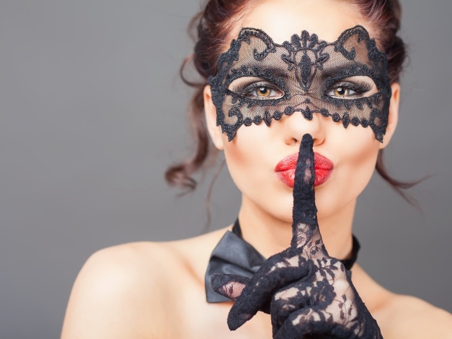 Девушка в черной маске с рукой в перчатке у лица