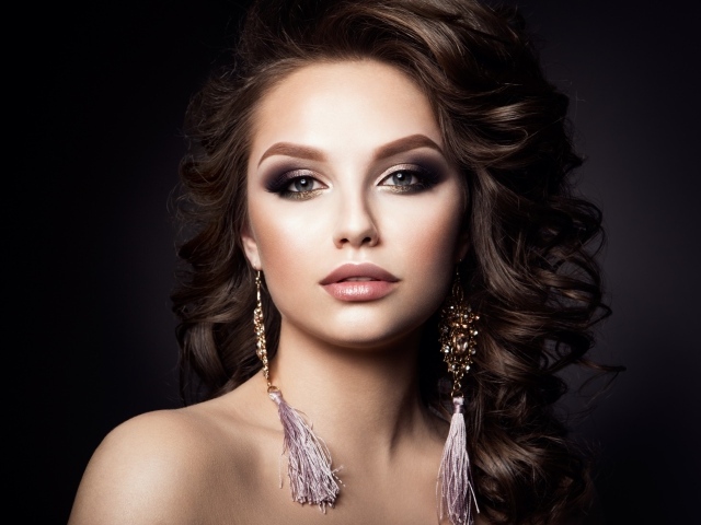 Девушка с прической с красивыми сережками на сером фоне 