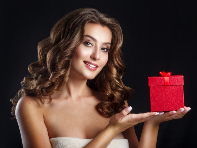 Девушка с красивыми волосами с подарком на руке 