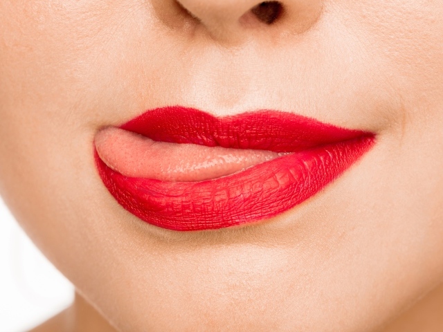 Девушка с  красными губами показывает язык