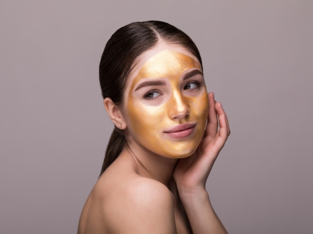 Золотая маска на лице у молодой девушки 