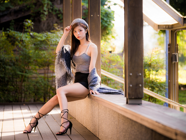 Длинноногая азиатка сидит на окне 