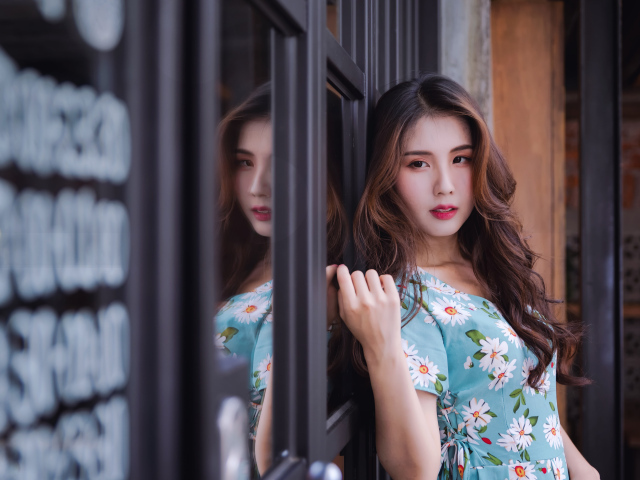 Длинноволосая девушка азиатка стоит у окна