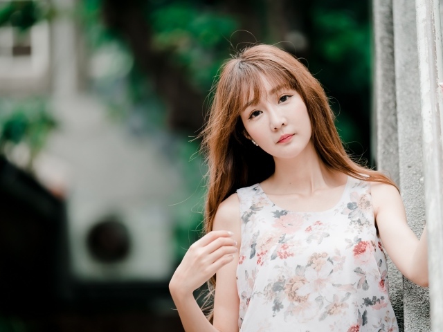 Длинноволосая азиатка стоит у стены 