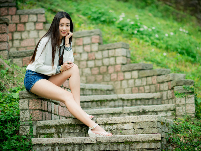 Длинноволосая девушка азиатка сидит на старых ступенях 
