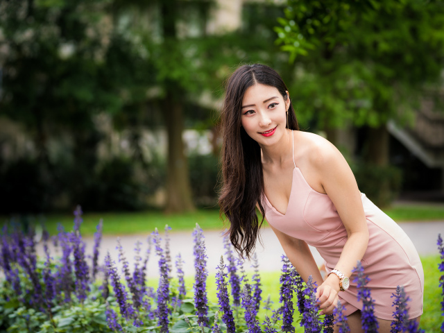 Милая девушка Азиатка в розовом платье у синих цветов