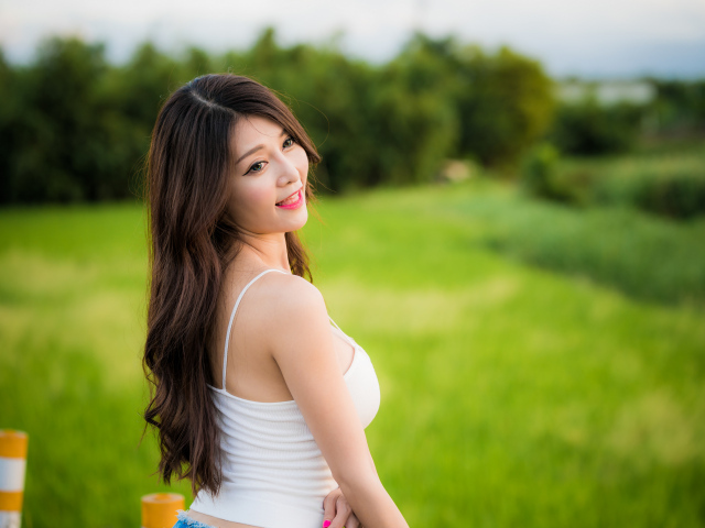 Улыбающаяся девушка азиатка на фоне зеленой травы