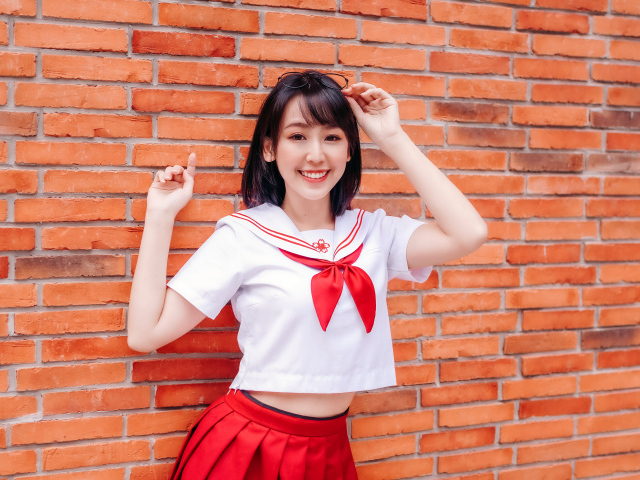 Улыбающаяся азиатка стоит у стены 