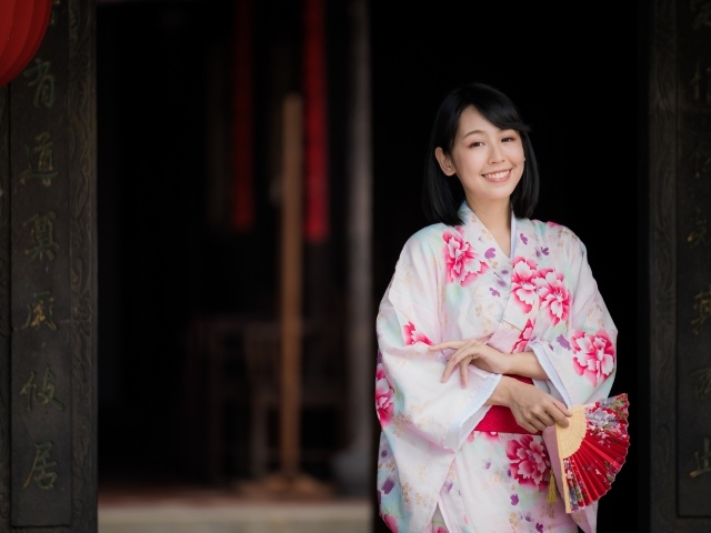 Улыбающаяся девушка азиатка в кимоно с веером в руке