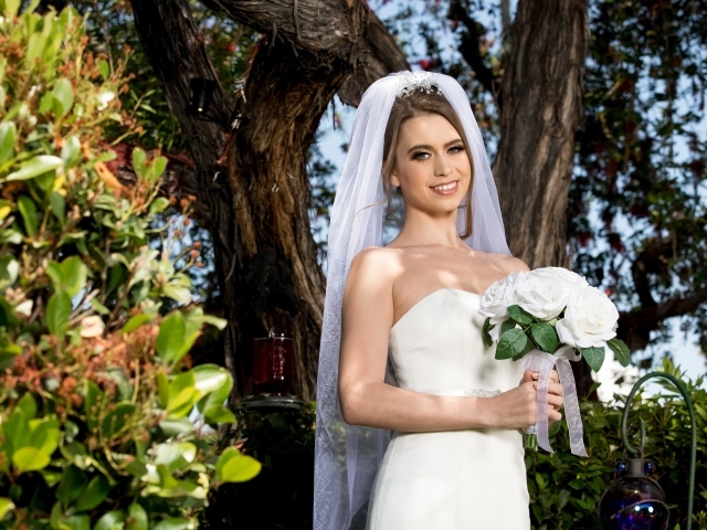 Улыбающаяся девушка в свадебном платье с букетом