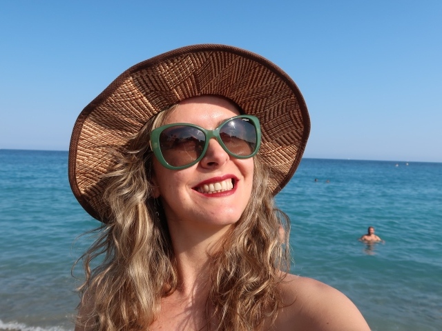 Улыбающаяся девушка в солнечных очках и шляпе на море