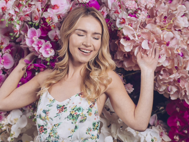 Улыбающаяся счастливая девушка у цветов орхидеи