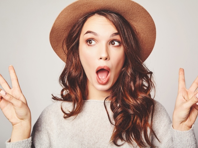 Удивленная девушка с длинными волосами в коричневой шляпе 