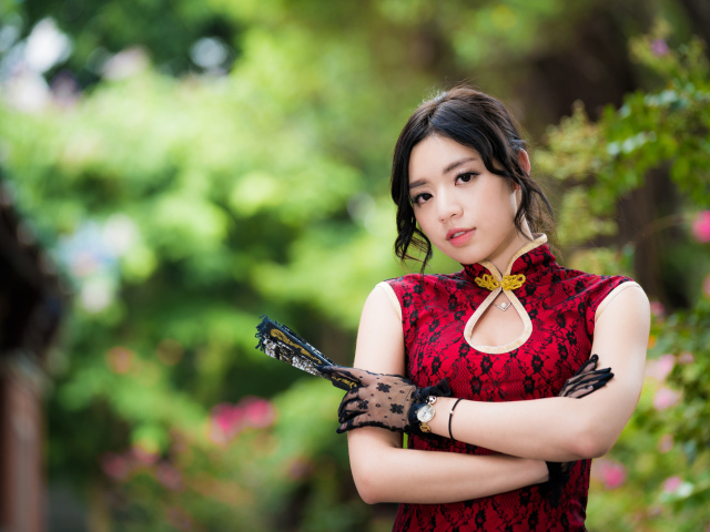 Молодая азиатка в красивом платье с веером в руке