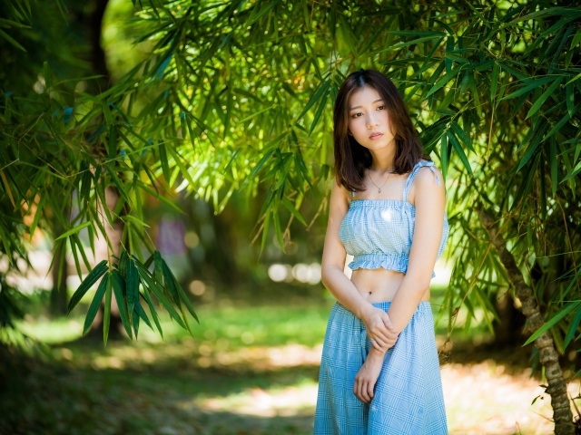 Молодая девушка в голубом костюме под деревом