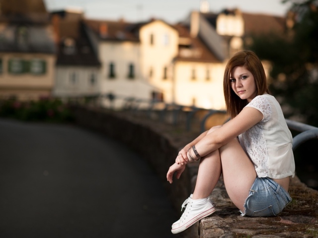 Молодая девушка с короткими  волосами сидит на улице