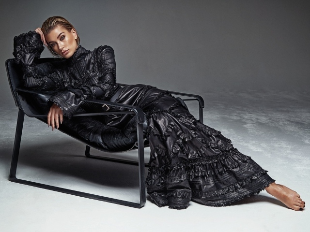 Красивая модель Хейли Болдуин в длинном платье лежит в кресле