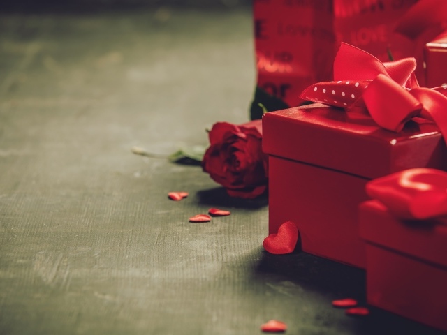 Красные коробки с подарками на столе с розой 