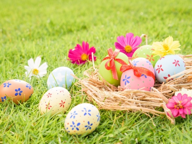 Разноцветные яйца в гнезде на зеленой траве на Пасху
