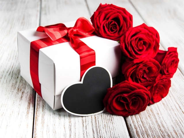 Букет красивых красных роз на столе с подарком для любимой на 8 марта