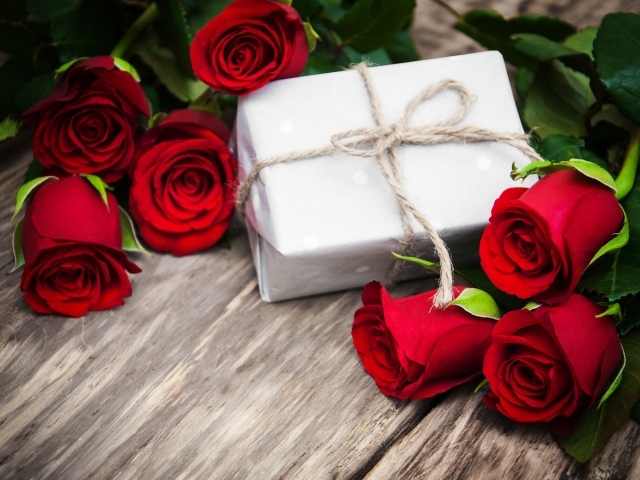 Букет красных роз на столе с подарком на 8 марта