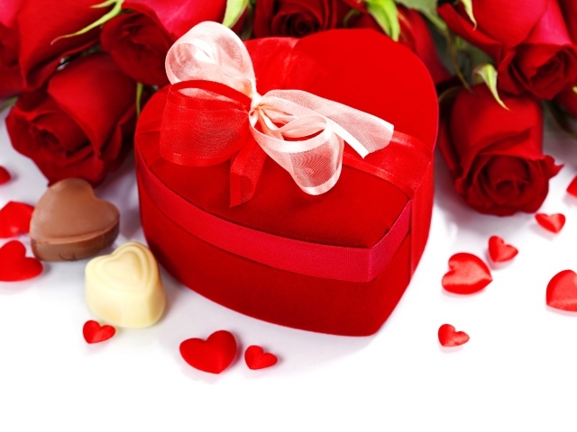 Красная коробка в форме сердца на столе с розами и конфетами для любимой