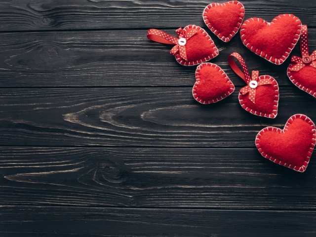 Много красных сердечек из фетра на деревянном столе