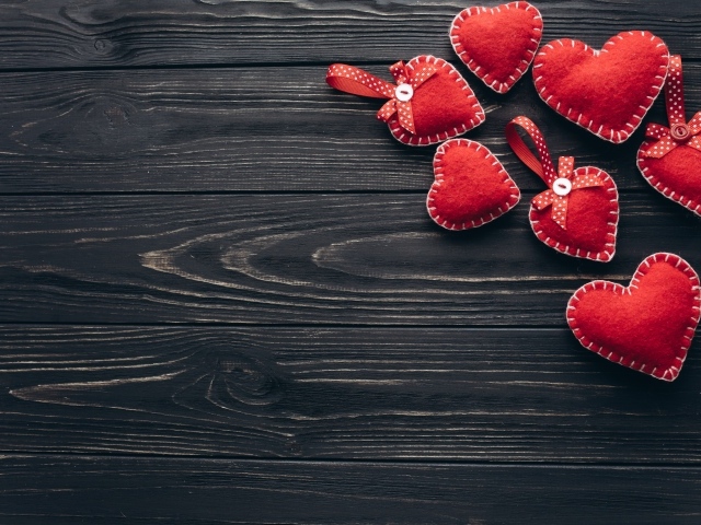 Много красных сердечек из фетра на деревянном столе