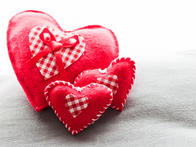 Сердечки из ткани лежат на серой поверхности 